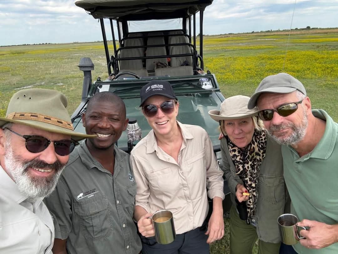 Guests and guide smiling in a safari vehicle